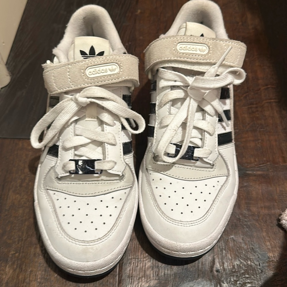 These sneakers have black and white marbling on the stripes and a suede strap.